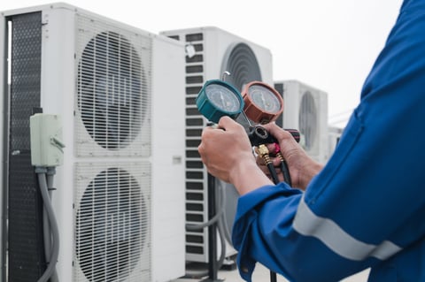 Technician checking air conditioner with measuring equipment