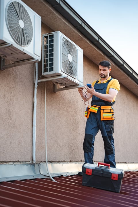 Air conditioner technician installing an air conditioning unit on a roof
